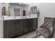 Bathroom featuring dual sinks with dark cabinets and a decorative chair at 3558 Herodain Ave, Las Vegas, NV 89106