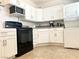 Bright kitchen featuring white cabinets, black appliances, a stainless steel sink, and tile flooring at 4193 W Warm Springs Rd, Las Vegas, NV 89118