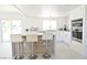 Stylish white kitchen with stainless steel appliances and a cozy island featuring three bar stools at 4193 W Warm Springs Rd, Las Vegas, NV 89118
