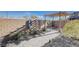 Lush backyard with a stone-paved walkway, decorative wall fountain, and a pergola-covered fire pit area at 422 Barcarolle Ln, Henderson, NV 89011