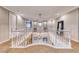 Elegant upper hallway with double chandeliers and white railings at 61 Contrada Fiore Dr, Henderson, NV 89011