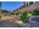 Gravel ground cover with a retaining wall lined with lush greenery and accent lighting at 1945 Canyon Highlands Dr, Henderson, NV 89052