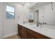 Modern bathroom featuring dual sinks, wood cabinets, a large mirror, and a bright window at 1945 Canyon Highlands Dr, Henderson, NV 89052