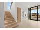 Bright entryway with wood stairs, minimalist decor and expansive sliding glass doors to the outside at 21 Grey Owl Ct, Las Vegas, NV 89135