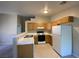 Kitchen with breakfast bar featuring wooden cabinets, white appliances and tile floors at 2110 Los Feliz St # 2052, Las Vegas, NV 89156