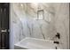 Bright bathroom features a white tub with marble-style tile and matte black fixtures at 4871 Charlemagne Ave, Las Vegas, NV 89130