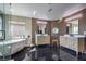 Sleek bathroom features a soaking tub, dual vanities, and black marble floors at 4871 Charlemagne Ave, Las Vegas, NV 89130