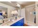 Bright bathroom boasts a double vanity with blue cabinetry, neutral countertops, and a tiled shower-tub combo at 5105 Kingsbridge Dr, Las Vegas, NV 89130