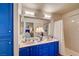Bathroom featuring dual sinks, blue cabinets and a shower with white tile at 5105 Kingsbridge Dr, Las Vegas, NV 89130