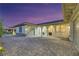 Stunning home exterior featuring a three-car garage and covered porch illuminated at dusk at 6425 Orto Botanico Ct, Las Vegas, NV 89131