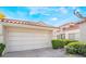 Two-car garage with a paved driveway surrounded by green landscaping and a tile roof under a blue sky at 6914 Emerald Springs Ln, Las Vegas, NV 89113