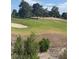 Beautiful view of a golf course with green grass, mature trees, and a sand trap at 6914 Emerald Springs Ln, Las Vegas, NV 89113
