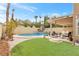 Inviting backyard oasis with a sparkling pool, covered patio, and lush grass at 9377 Lotus Elan Dr, Las Vegas, NV 89117