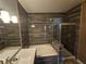 Elegant bathroom featuring a separate tub and glass-enclosed shower with dark wood-style wall tiles at 8309 Cherry Glaze Ave # 201, Las Vegas, NV 89145