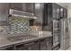This kitchen shows a gas cooktop, stainless vent hood, granite counters, and stainless appliances at 1189 Hillside Peak St, Henderson, NV 89002