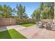 Brick paved backyard featuring artificial turf, a patio table set, and block wall at 2905 Vigilante Ct, North Las Vegas, NV 89081