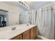 Bathroom featuring dual sinks and a large mirror, complemented by a shower with curtains at 2905 Vigilante Ct, North Las Vegas, NV 89081