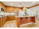 Well-lit kitchen features tile floors, center island with granite counters, and wood cabinets at 395 Suzanne Peak Ct, Henderson, NV 89012