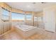 Serene main bathroom features a tub, shower, and lovely views from multiple large windows at 395 Suzanne Peak Ct, Henderson, NV 89012