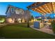 Backyard offers a lush lawn, patio with outdoor seating under a pergola with lighting, and mature trees at 3372 Dalmore St, Henderson, NV 89044