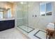 A luxurious bathroom with a glass-enclosed shower, marble tile, a rainfall shower head and bench at 3372 Dalmore St, Henderson, NV 89044