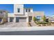 View of a modern home exterior featuring a three-car garage, desert landscaping, and a paved brick driveway at 3372 Dalmore St, Henderson, NV 89044