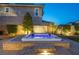 A tranquil backyard featuring a lighted hot tub and waterfall against the backdrop of the home's exterior at 3372 Dalmore St, Henderson, NV 89044