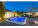 Backyard view of a luxurious, lighted hot tub alongside a stone waterfall, mature landscaping, and paved patio at 3372 Dalmore St, Henderson, NV 89044