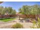 Desert-landscaped backyard featuring artificial turf, a fire pit, and mature shade trees at 8005 Egypt Meadows Ave, Las Vegas, NV 89178
