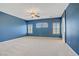 Spacious blue-walled bedroom with ceiling fan and natural light from shuttered windows at 8005 Egypt Meadows Ave, Las Vegas, NV 89178