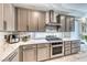 Modern kitchen with stainless steel oven, cooktop, and gray cabinets complemented by light marble countertops and backsplash at 29 Sun Mirage Ave, Henderson, NV 89011