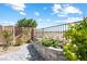 Landscaped backyard featuring a flower bed, paved walkway, and metal fence under a blue sky at 3543 E Wallowa Dr, Pahrump, NV 89061