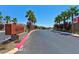 Community entrance with a sign, palm trees, and colorful landscaping at 3634 Tripoli Cove Ave, Las Vegas, NV 89106