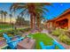 Picturesque backyard with palm trees, lush turf, gravel hardscape, and cozy seating area at 453 Via Palermo Dr, Henderson, NV 89011