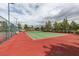 Outdoor tennis court with vibrant green playing surface and red perimeter, surrounded by fencing and landscaping at 5805 Hannah Brook St, North Las Vegas, NV 89081