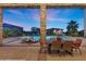 Covered patio featuring an outdoor dining set with a view of the pool and lush backyard landscaping at 670 Du Fort Ave, Henderson, NV 89002