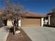 Attached garage with ample parking space and a tree in the front at 7588 Kalmalii Ave, Las Vegas, NV 89147