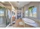 This bathroom features double sinks, a shower, soaking tub, and bright windows with tiled floors at 7936 Tolberts Mill Dr, Las Vegas, NV 89131