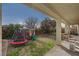 Large backyard with grassy area, playset, and covered patio at 8870 S Tenaya Way, Las Vegas, NV 89113