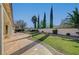 Expansive backyard featuring a concrete patio, a lawn separated by gravel, plus tall Italian Cypress trees and bushes at 9843 Wonderful Day Dr, Las Vegas, NV 89148