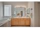 Bright bathroom featuring dual sinks with wooden cabinets, large mirror, soaking tub, and a window at 9843 Wonderful Day Dr, Las Vegas, NV 89148