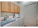 Practical laundry room equipped with washer, dryer, and wooden cabinets for storage at 9843 Wonderful Day Dr, Las Vegas, NV 89148