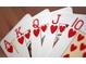 A close-up of a royal flush of hearts; Ace, King, Queen, Jack, and 10 displayed on a wood surface at 9843 Wonderful Day Dr, Las Vegas, NV 89148