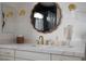 Close-up of a bathroom vanity featuring brass fixtures, marble countertop, decorative mirror, and modern lighting at 10420 Luella Ct, Las Vegas, NV 89143