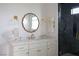 Close-up of a bathroom vanity with brass fixtures, a modern mirror, marble countertop, and gray-tiled shower at 10420 Luella Ct, Las Vegas, NV 89143