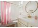 Well-lit bathroom featuring a vanity with gold hardware and a bathtub with a pink striped curtain at 10420 Luella Ct, Las Vegas, NV 89143