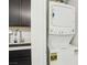 Convenient laundry area featuring a stacked washer and dryer next to a kitchenette at 1209 Crystal Grotto Ave, North Las Vegas, NV 89081