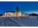 Night shot of a well-lit single-story home featuring a three car garage and stylish landscaping at 1691 Blackhorn St, Pahrump, NV 89048