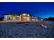 Night shot of a well-lit single-story home featuring a three car garage and stylish landscaping at 1691 Blackhorn St, Pahrump, NV 89048