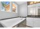 Bathroom with tiled floors, a granite countertop, and a large soaking tub next to bright windows at 24 Cerchio Alto, Henderson, NV 89011